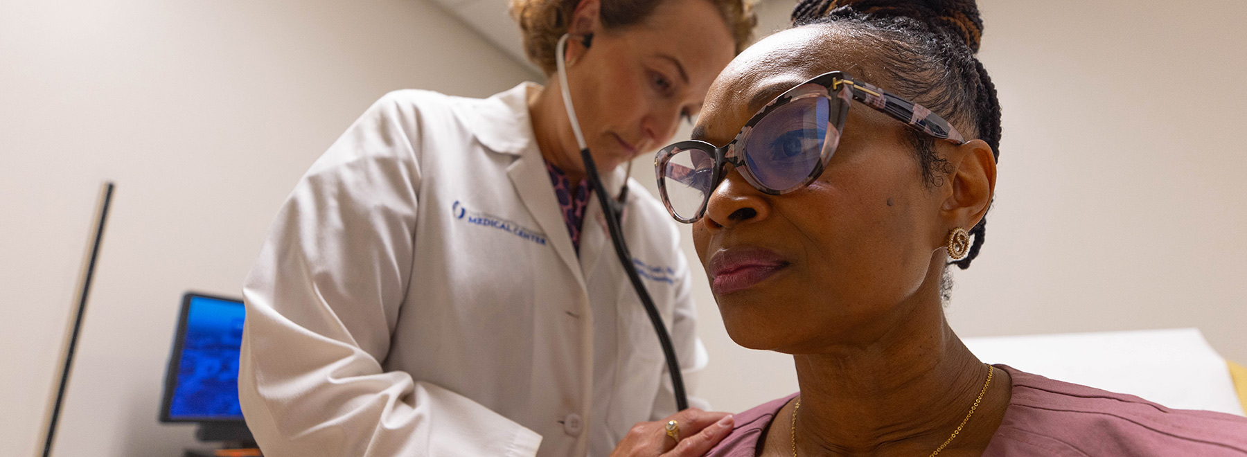 A doctor examining a breast cancer patient with a stethoscope. A doctor examining a breast cancer patient with a stethoscope.